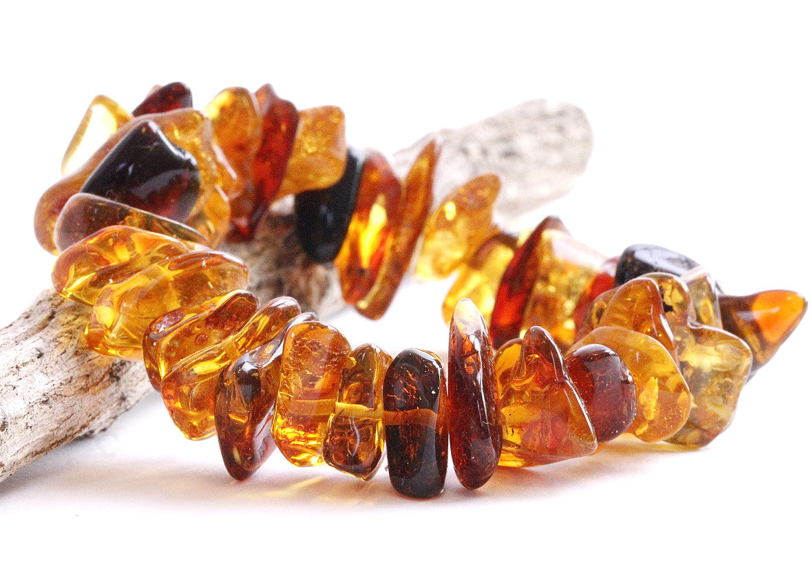 A close-up image of a retro-style amber bracelet composed of natural amber beads with varying hues and patterns.