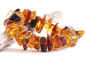A close-up image of a retro-style amber bracelet composed of natural amber beads with varying hues and patterns.