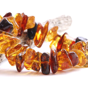 A close-up image of a retro-style amber bracelet composed of natural amber beads with varying hues and patterns.